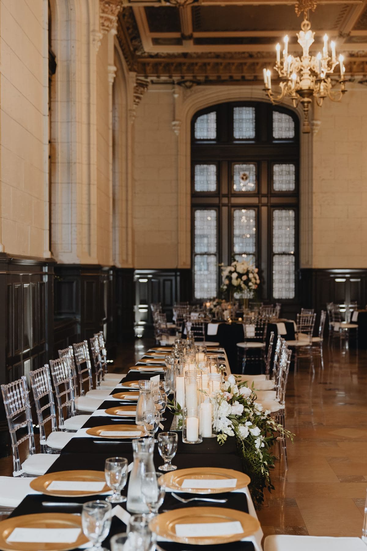 A long dinner table with black linens and candles