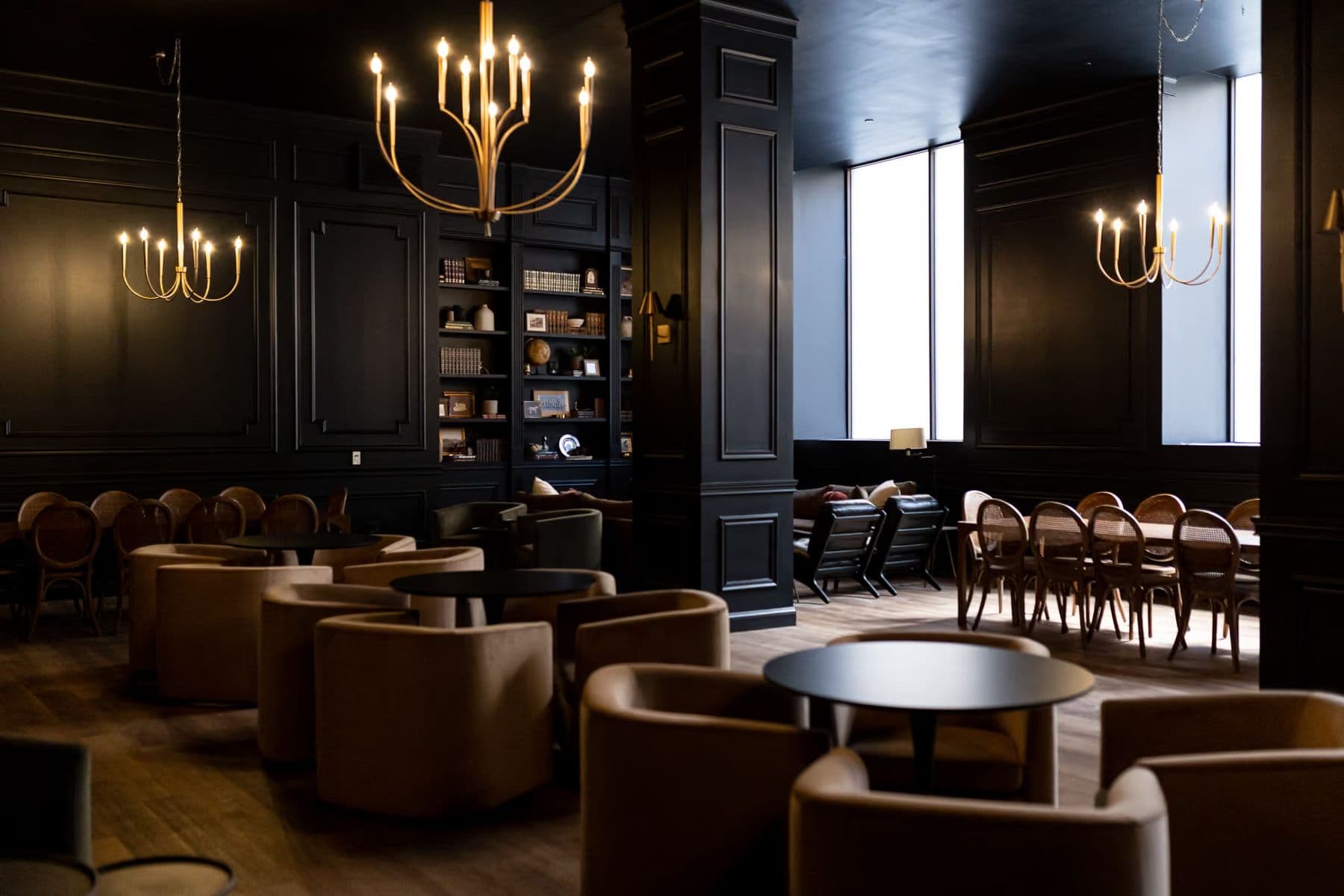 A couple shares a first dance in Noir, beneath a brass chandelier and dark bookshelves